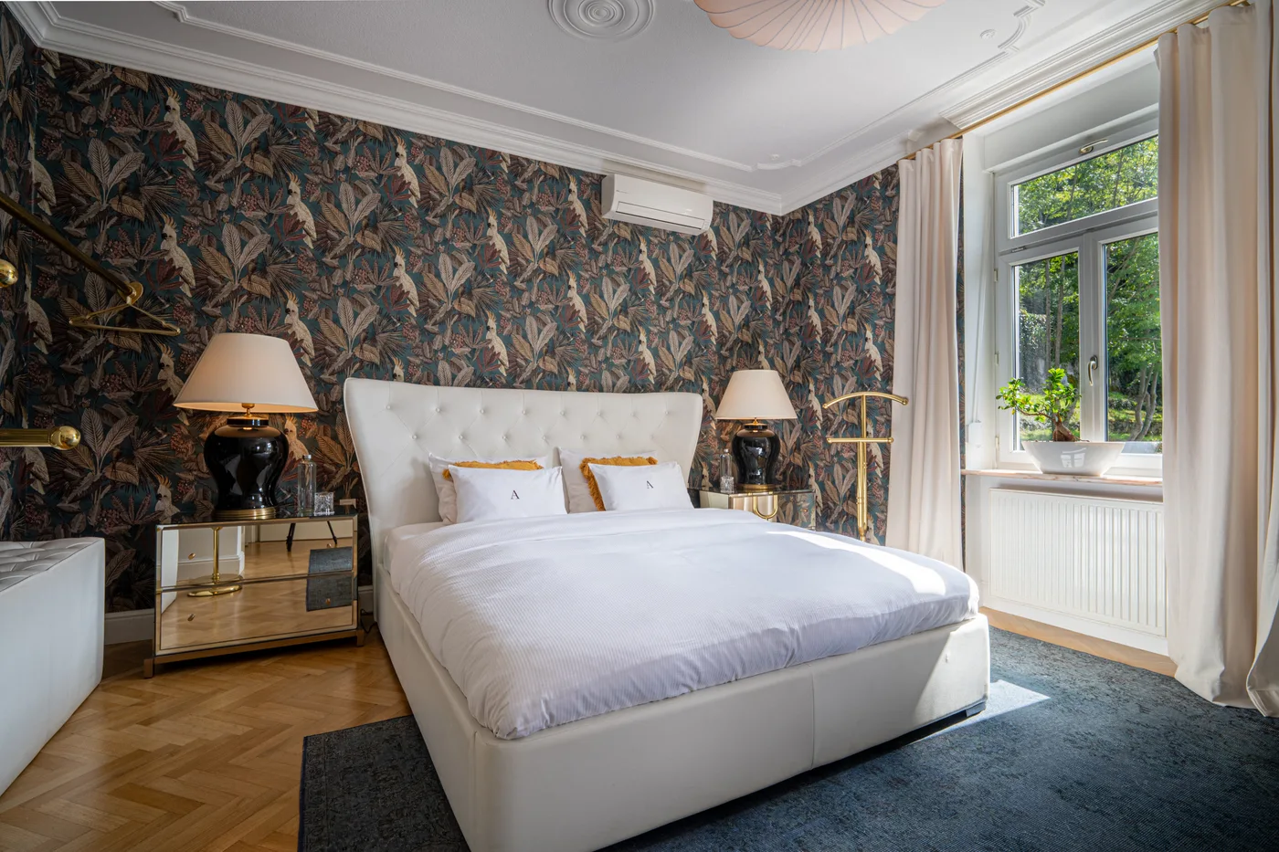 Deluxe Suite bedroom with botanical wallpaper and a white upholstered bed