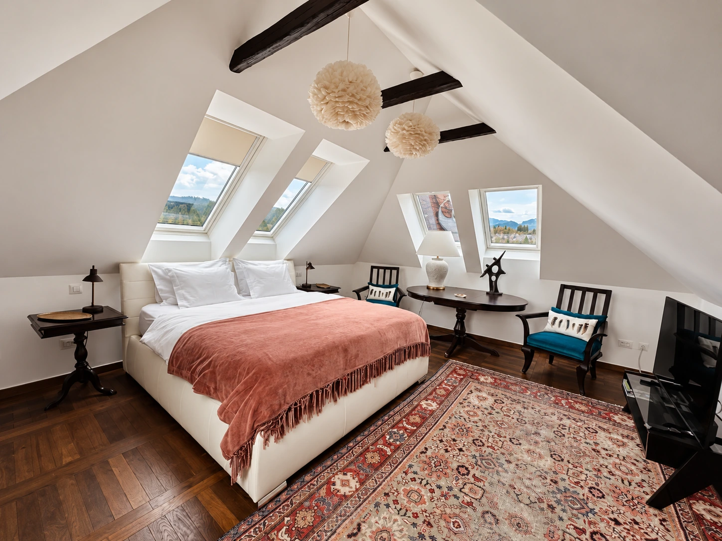 Penthouse bedroom beneath exposed beams and roof windows
